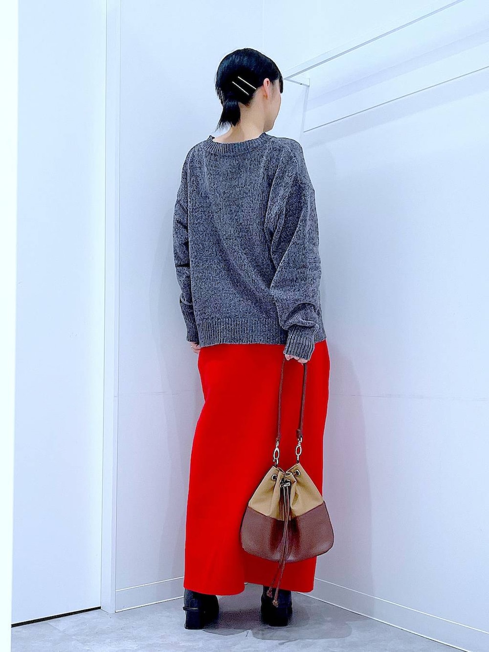 ベージュ系のショルダーバッグ、ブラック系のブーツ、グレー系のニット/セーターを着用したレディースの冬コーディネートの5枚目の写真