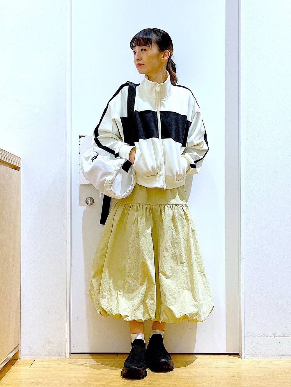 ベージュ系のブルゾン、ベージュ系のスカート、ホワイト系のショルダーバッグを着用したレディースの冬コーディネートの2枚目の写真