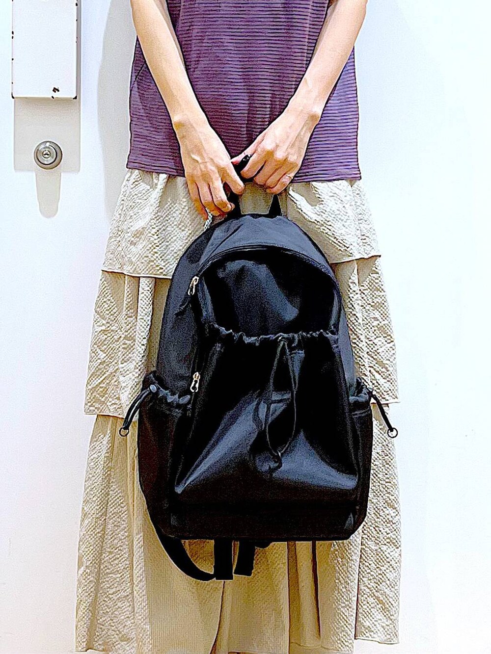 ブラウン系のTシャツ/カットソー、ベージュ系のスカート、ブラック系のバックパック/リュックを着用したレディースの春コーディネートの9枚目の写真