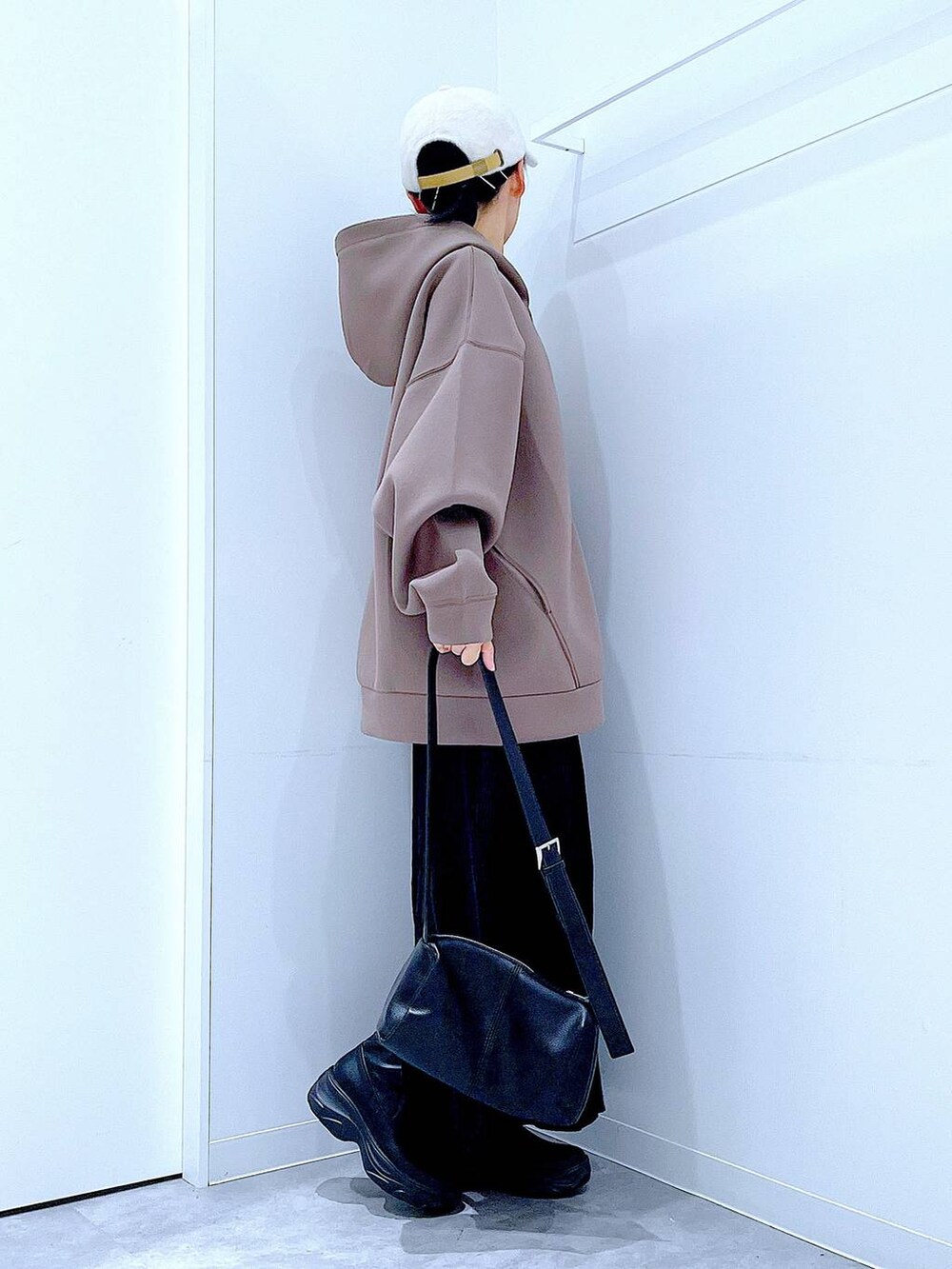 ブラック系のショルダーバッグ、ブラック系のブーツ、ブラウン系のパーカーを着用したレディースの秋コーディネートの4枚目の写真