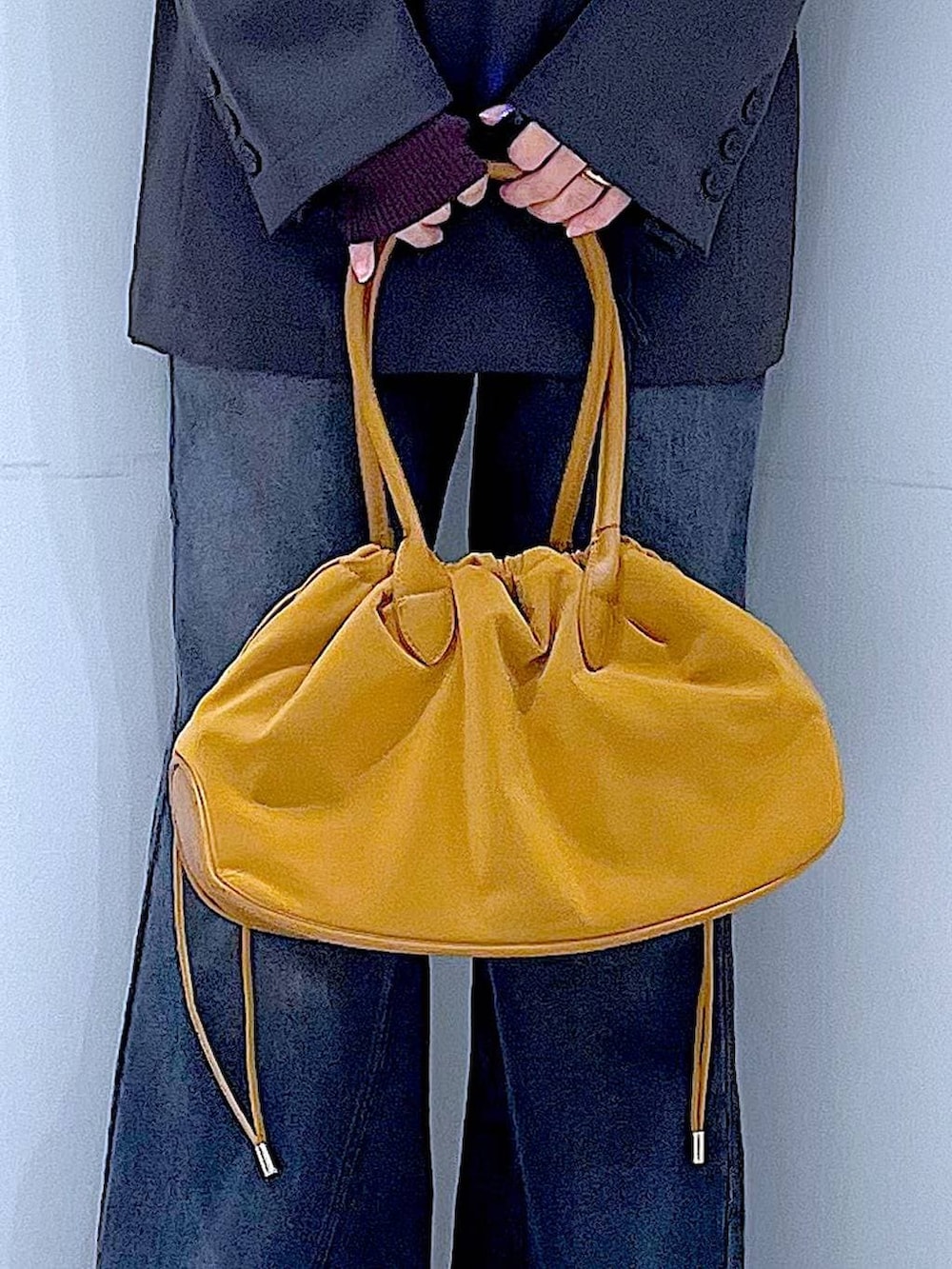 ブラウン系のハンドバッグ、ブラウン系のニット/セーター、グレー系のテーラードジャケットを着用したレディースの冬コーディネートの9枚目の写真