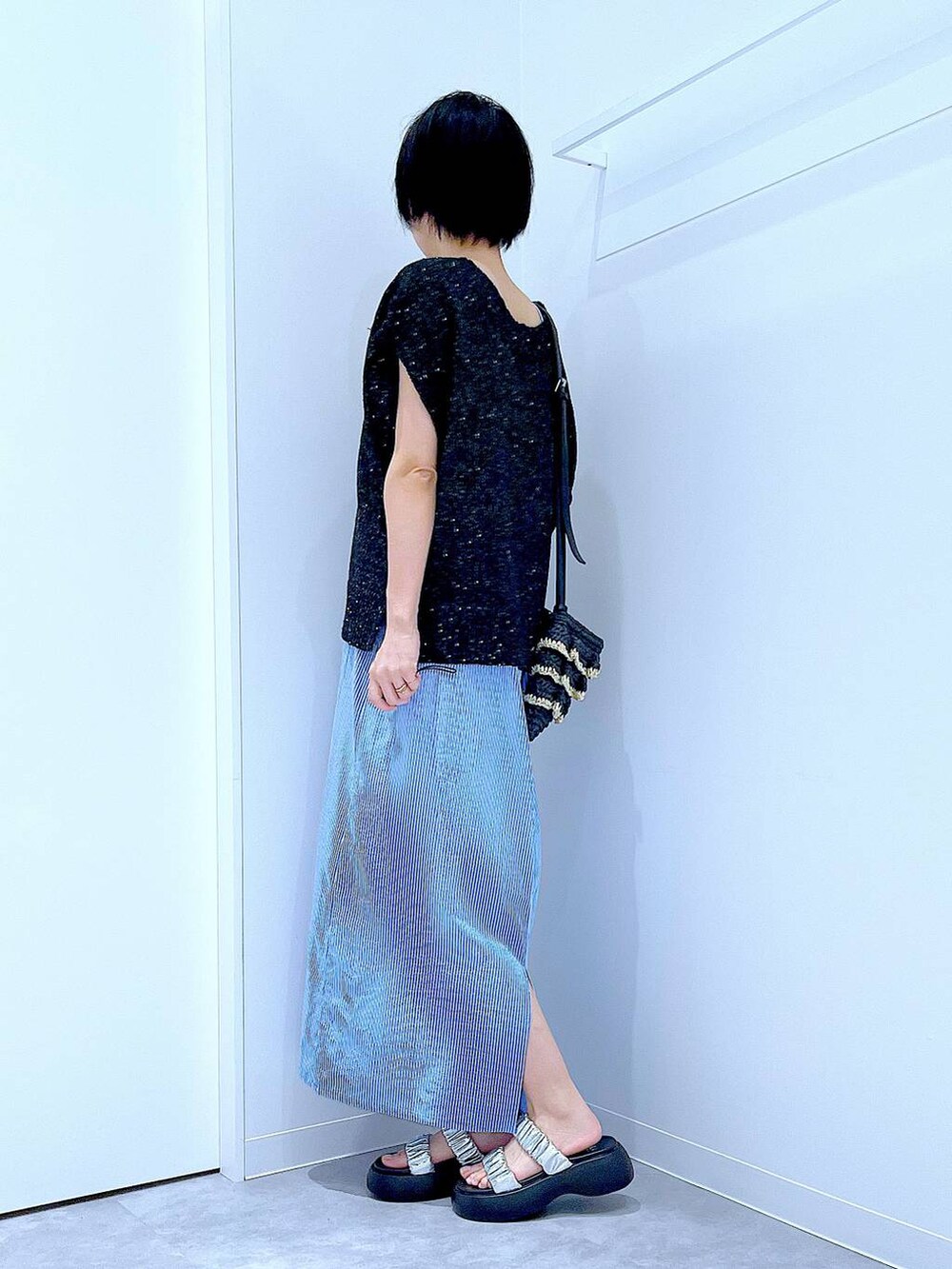 ブラック系のショルダーバッグ、シルバー系のサンダル、ブラック系のベストを着用したレディースの夏コーディネートの3枚目の写真