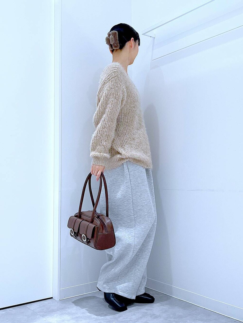 ブラウン系のショルダーバッグ、ブラック系のブーツ、グレー系のスウェットパンツを着用したレディースの冬コーディネートの4枚目の写真