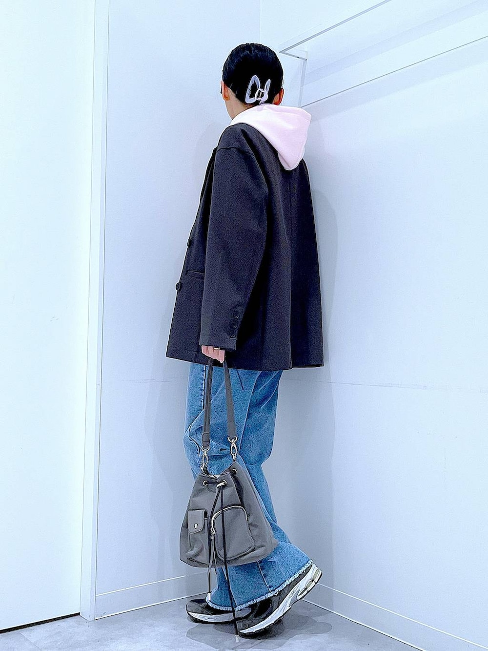 グレー系のテーラードジャケット、ブルー系のデニムパンツ、ピンク系のパーカーを着用したレディースの春コーディネートの3枚目の写真