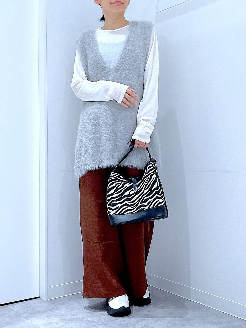 ホワイト系のTシャツ/カットソー、ホワイト系のローファー、グレー系のベストを着用したレディースの秋コーディネートの6枚目の写真