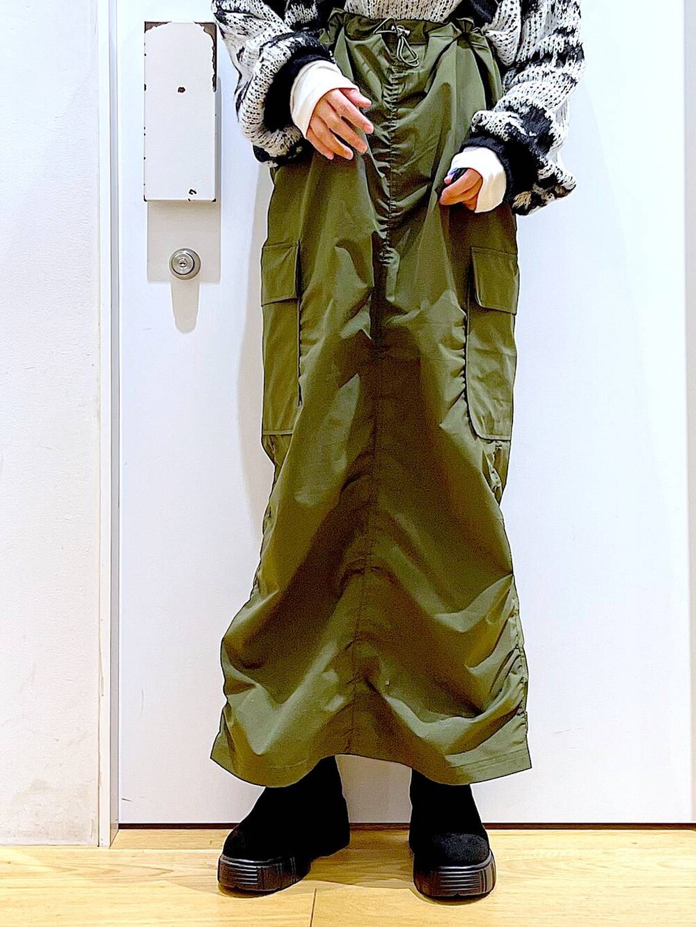 ホワイト系のトートバッグ、ベージュ系のTシャツ/カットソー、グリーン系のジャンパースカートを着用したレディースの冬コーディネートの8枚目の写真