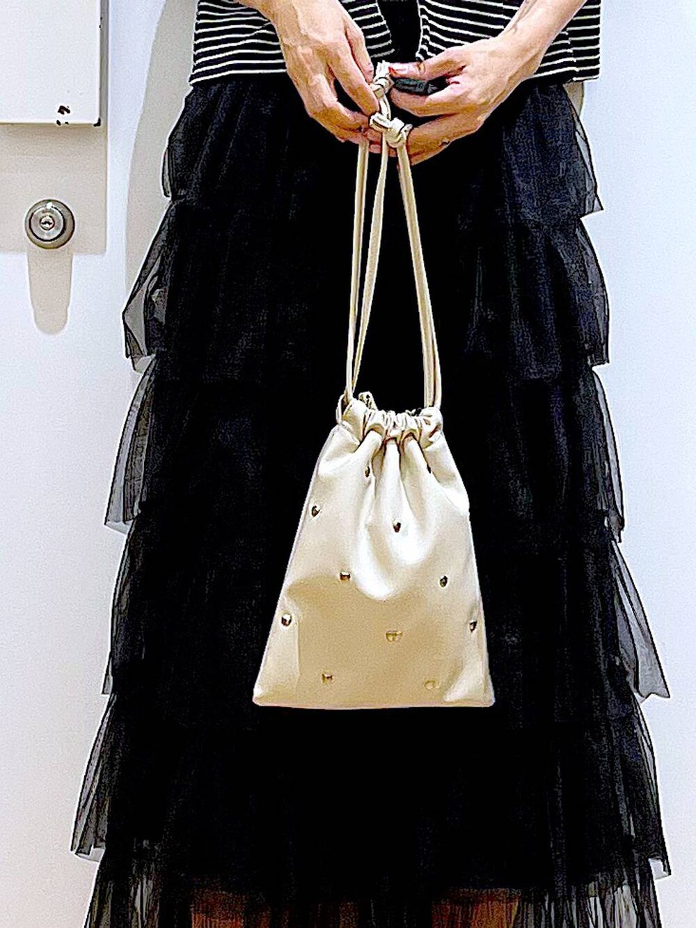 ホワイト系のサンダル、ホワイト系のショルダーバッグ、ブラック系のスカートを着用したレディースの夏コーディネートの9枚目の写真