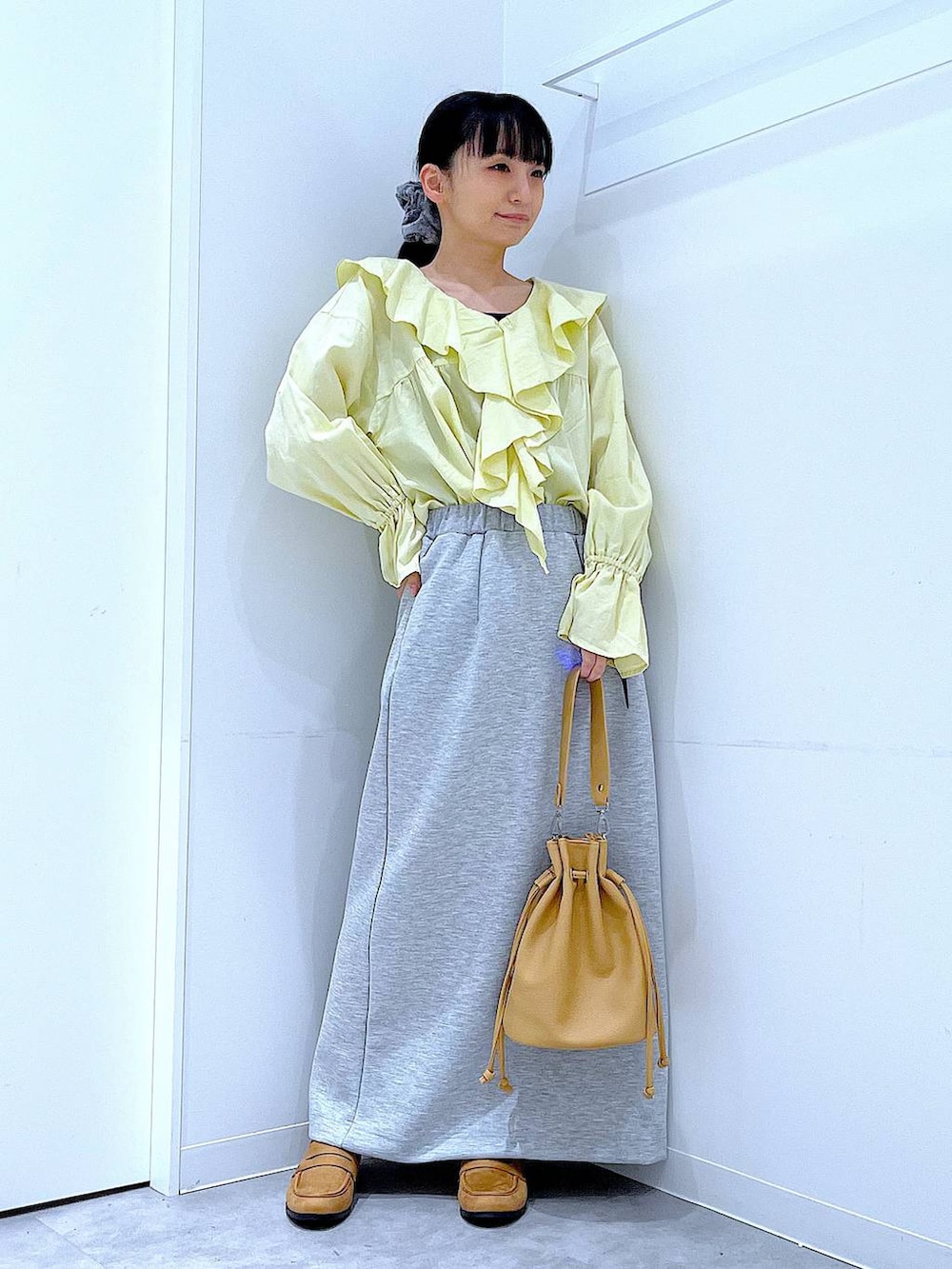 グレー系のスカート、ベージュ系のローファー、ブラウン系のショルダーバッグを着用したレディースの冬コーディネートの2枚目の写真