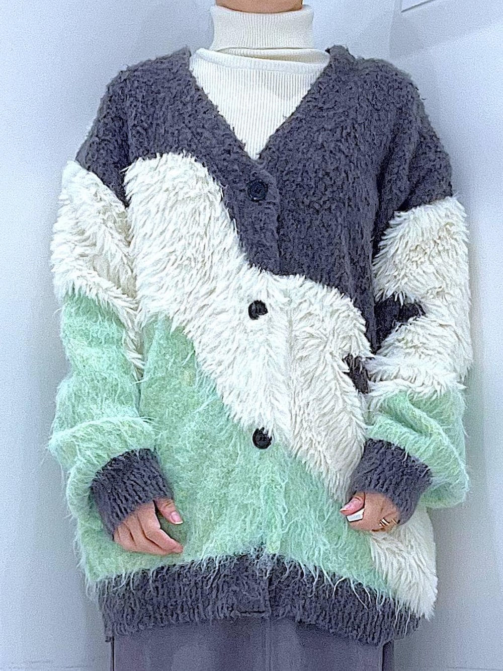 グリーン系のカーディガン/ボレロ、ブラック系のブーツ、ホワイト系のショルダーバッグを着用したレディースの冬コーディネートの7枚目の写真