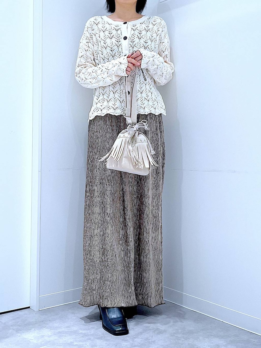 ブラック系のブーツ、ホワイト系のショルダーバッグ、ベージュ系のカーディガン/ボレロを着用したレディースの冬コーディネートの6枚目の写真