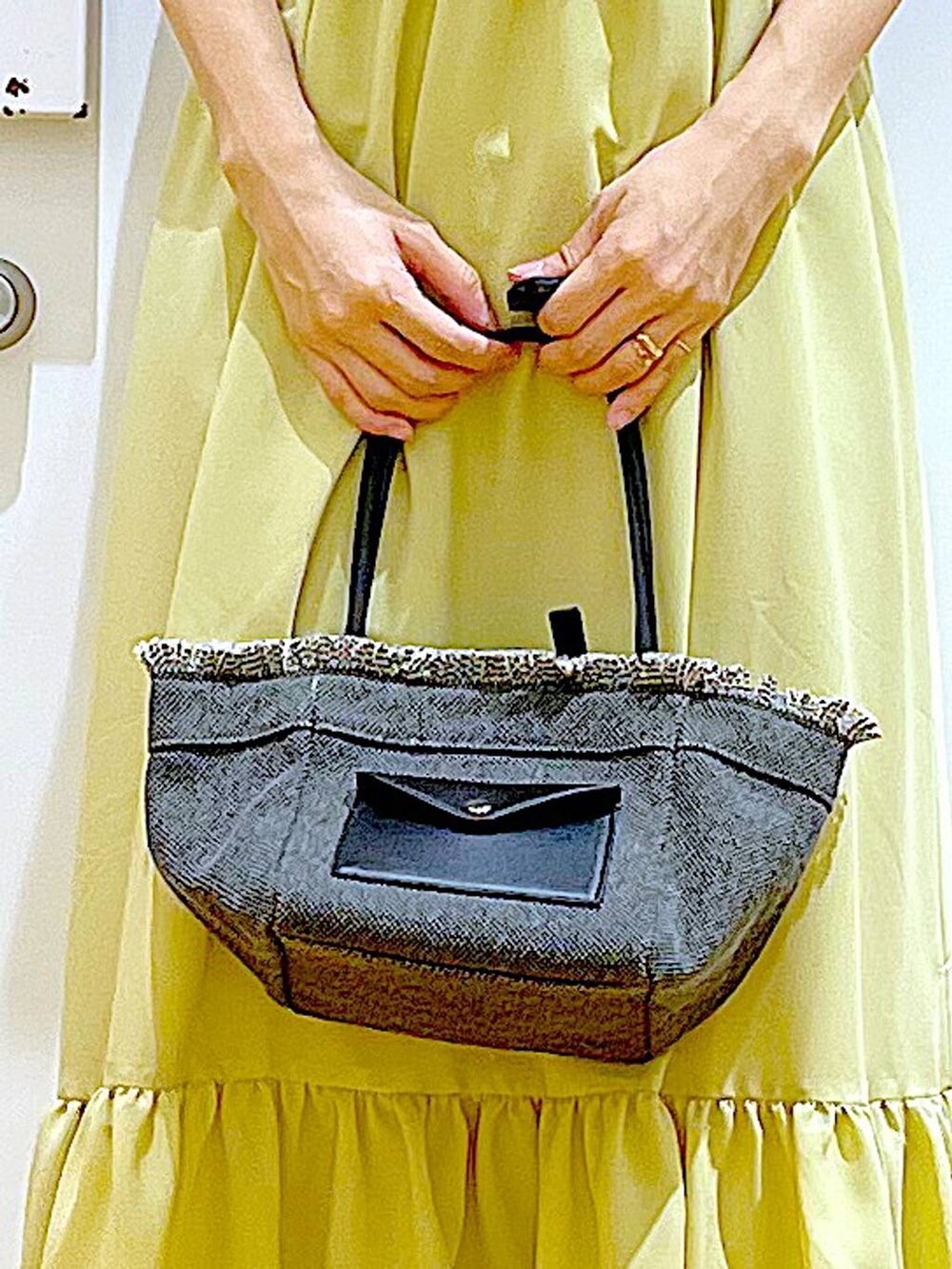 ブラック系のショルダーバッグ、ベージュ系のパンプス、イエロー系のワンピースを着用したレディースの春コーディネートの9枚目の写真