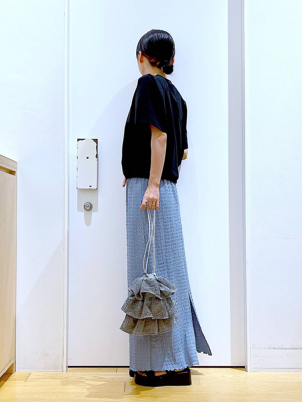 シルバー系のショルダーバッグ、ブルー系のスカート、ブラック系のTシャツ/カットソーを着用したレディースの夏コーディネートの3枚目の写真