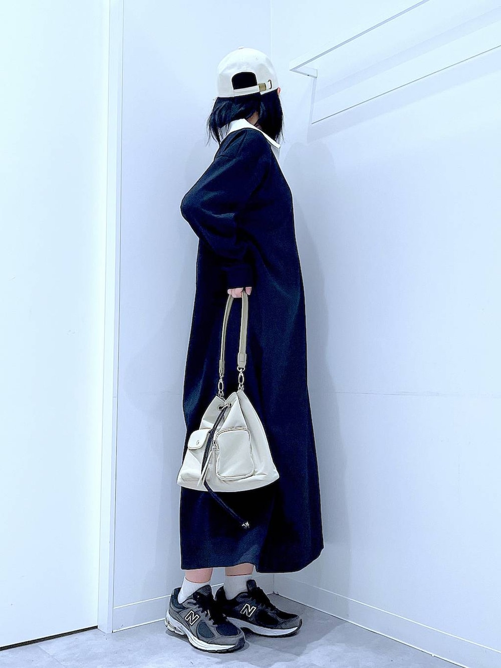 ホワイト系のショルダーバッグ、ブラック系のワンピース、ホワイト系のキャップを着用したレディースの春コーディネートの4枚目の写真