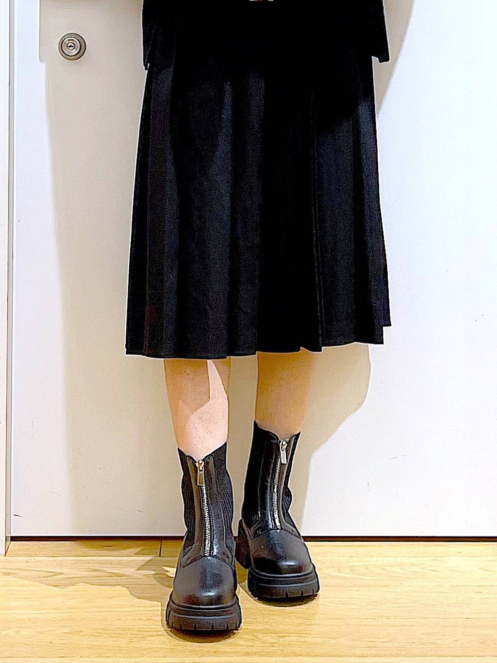 イエロー系のブルゾン、ブラック系のブーツ、ブラック系のスカートを着用したレディースの冬コーディネートの8枚目の写真