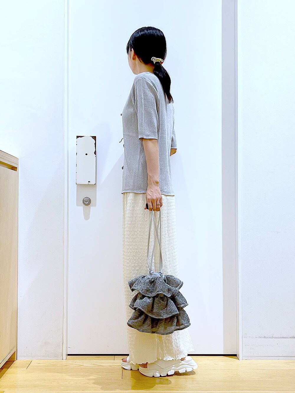 シルバー系のショルダーバッグ、ホワイト系のニット/セーター、ホワイト系のサンダルを着用したレディースの夏コーディネートの3枚目の写真