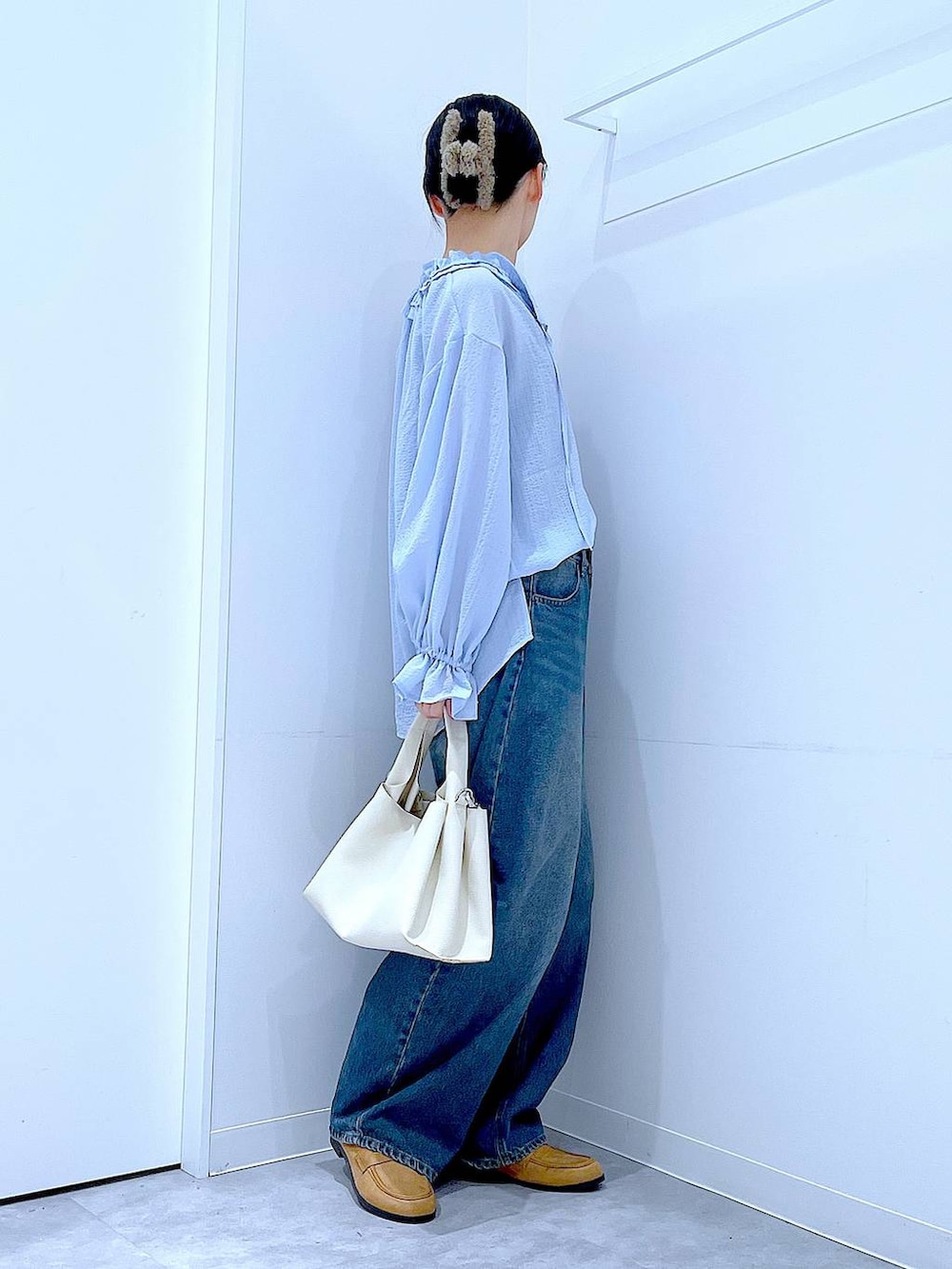 ブルー系のデニムパンツ、ベージュ系のローファー、ホワイト系のトートバッグを着用したレディースの春コーディネートの4枚目の写真