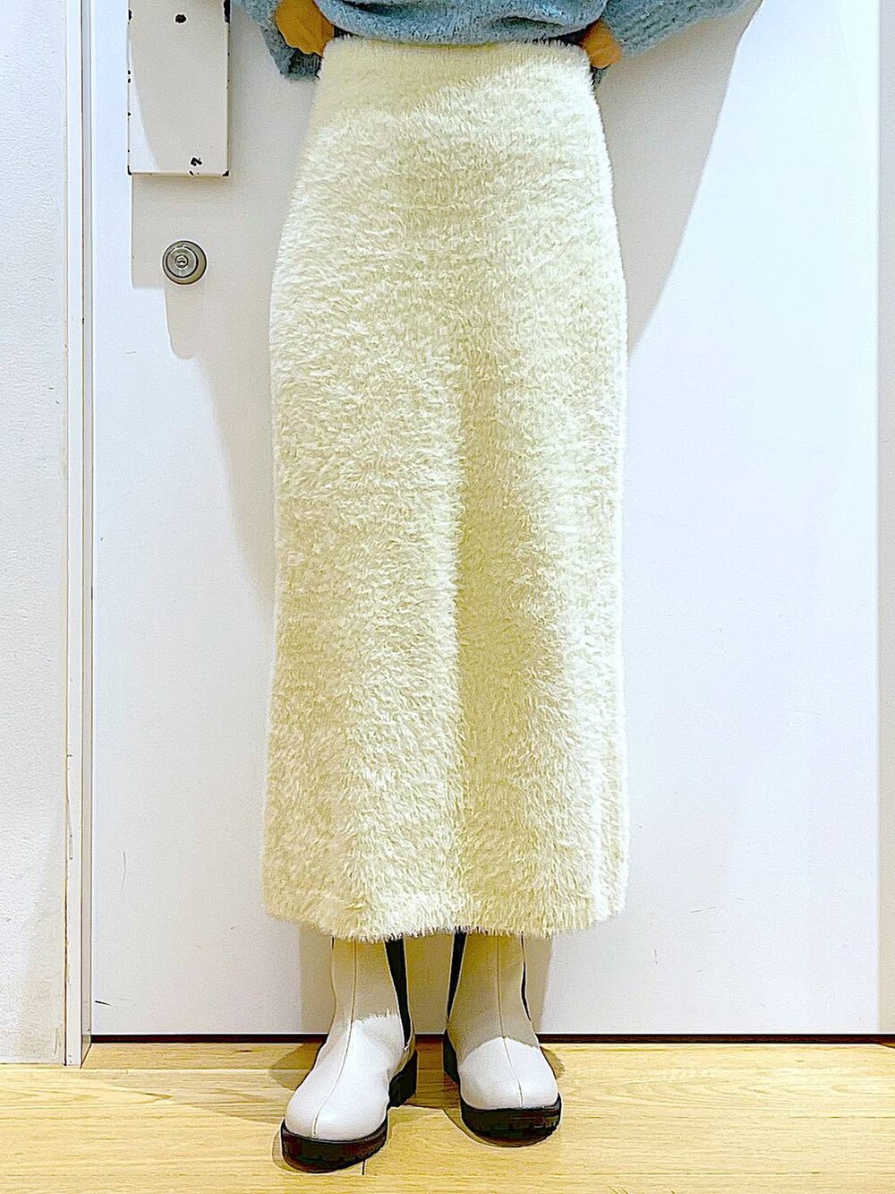 ホワイト系のショルダーバッグ、ベージュ系のブーツ、ホワイト系のスカートを着用したレディースの冬コーディネートの8枚目の写真