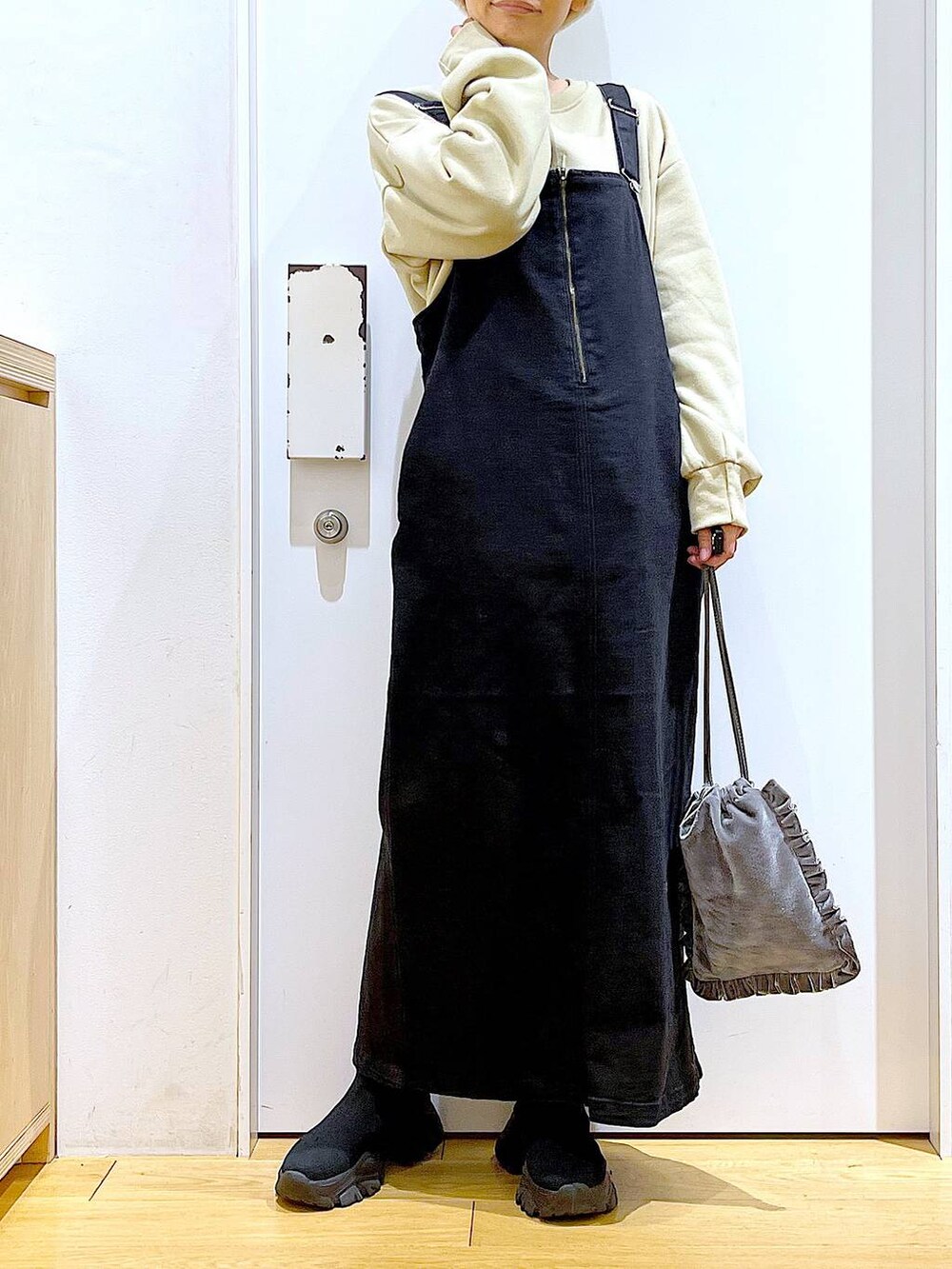 グレー系のジャンパースカート、グレー系のショルダーバッグ、ブラック系のブーツを着用したレディースの冬コーディネートの6枚目の写真