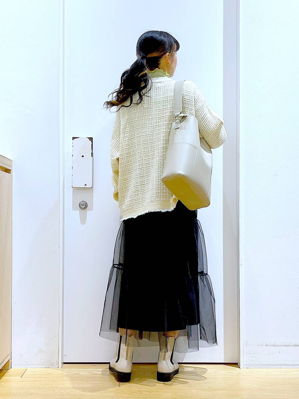 グレー系のショルダーバッグ、ベージュ系のブーツ、ブラック系のスカートを着用したレディースの冬コーディネートの5枚目の写真