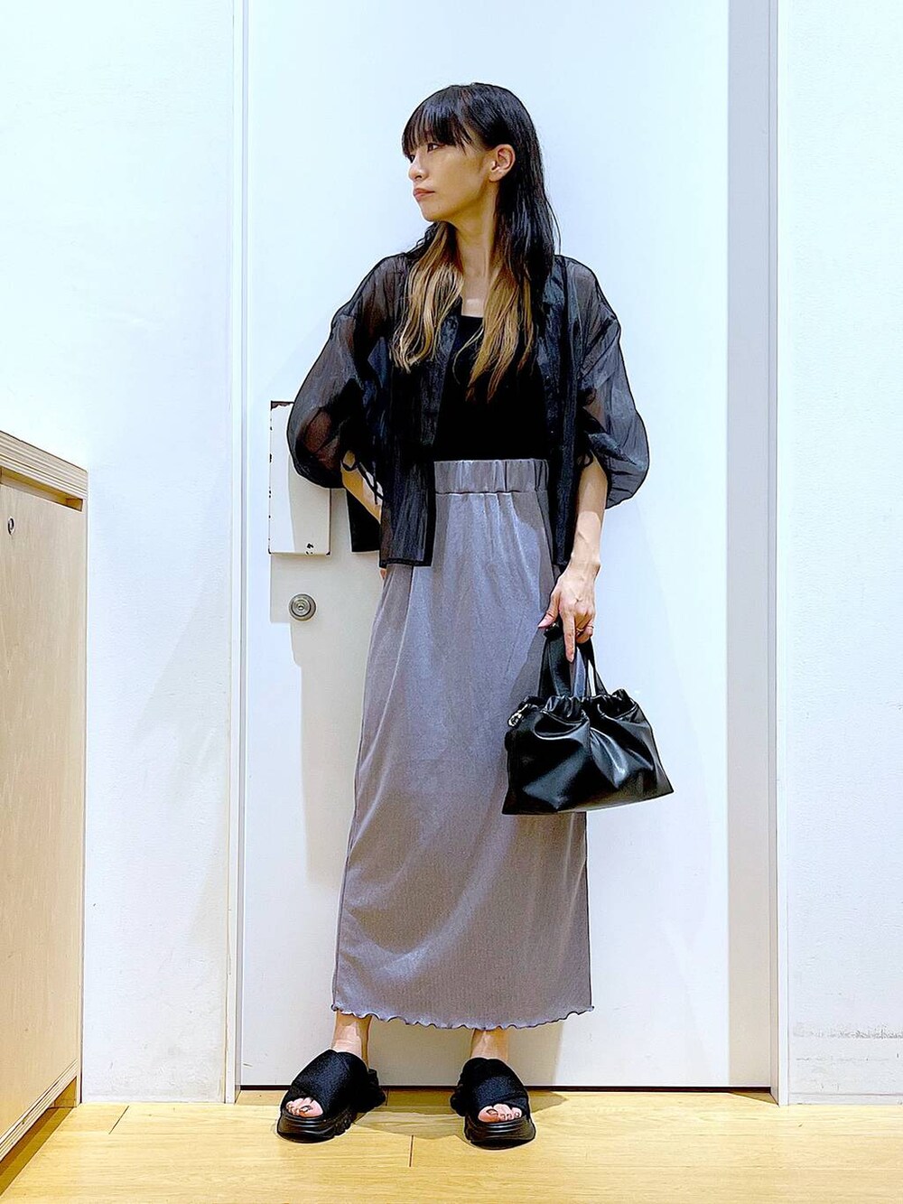 パープル系のスカート、ブラック系のサンダル、ブラック系のニット/セーターを着用したレディースの夏コーディネートの2枚目の写真