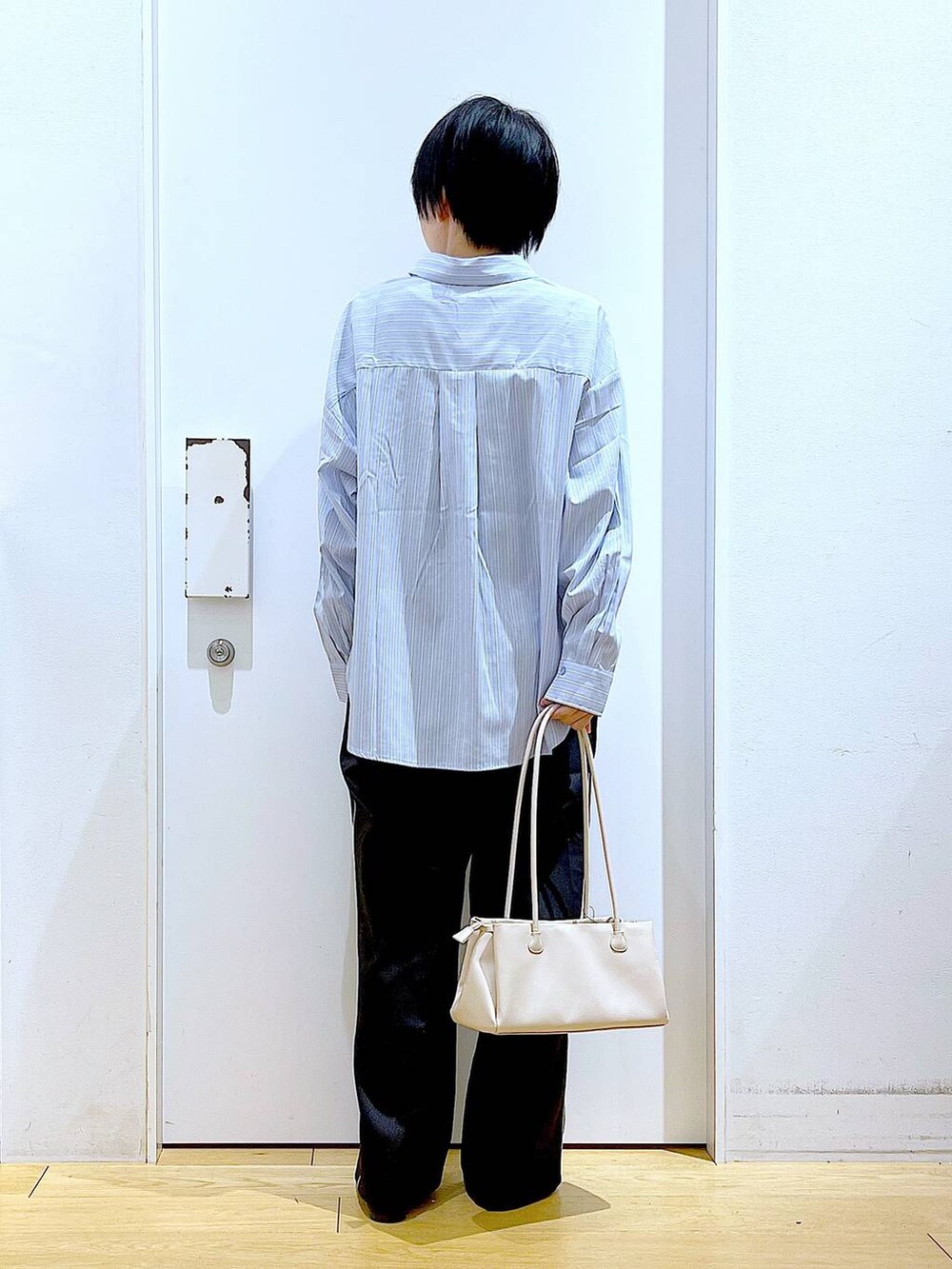 ブラック系のスラックス、ホワイト系のトートバッグ、ブラック系のパンプスを着用したレディースの春コーディネートの5枚目の写真