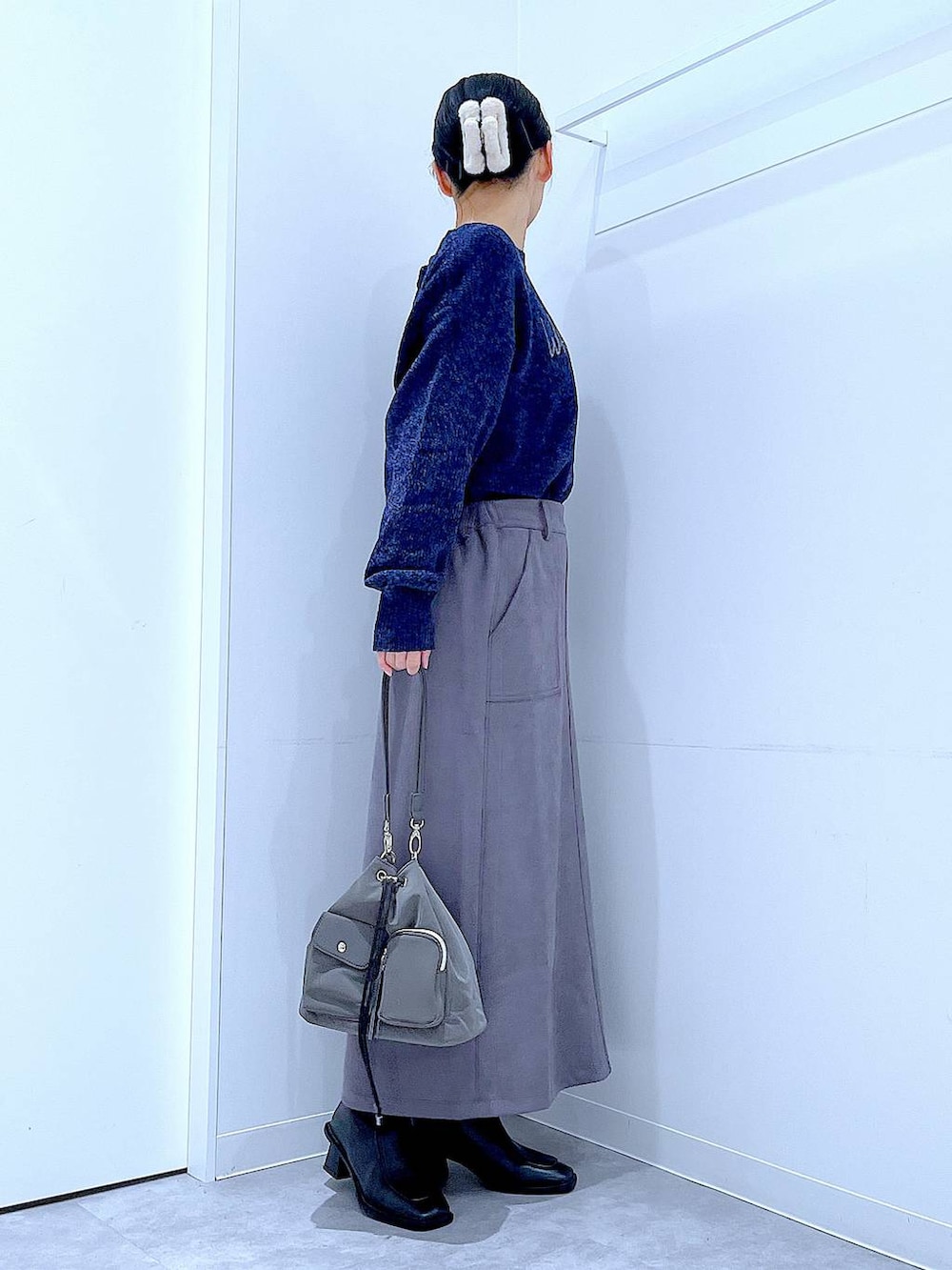 ブラック系のブーツ、ブルー系のニット/セーター、グレー系のスカートを着用したレディースの冬コーディネートの4枚目の写真