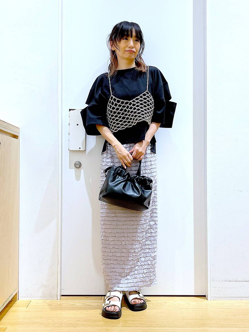 ホワイト系のサンダル、ブラック系のショルダーバッグ、シルバー系のベストを着用したレディースの夏コーディネートの2枚目の写真