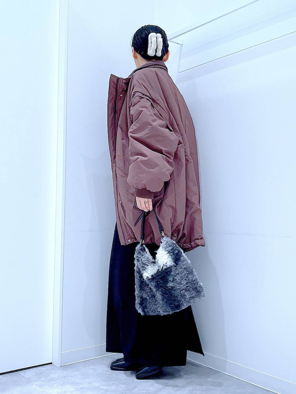 ブラウン系のブルゾン、ブラック系のブーツ、ブラック系のショルダーバッグを着用したレディースの冬コーディネートの3枚目の写真