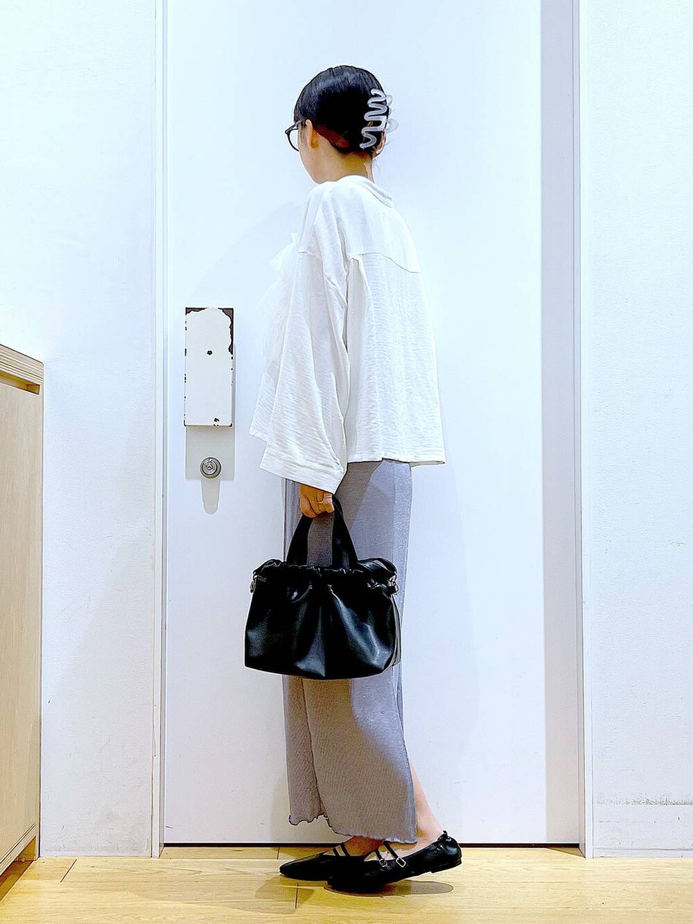 パープル系のスカート、ブラック系のショルダーバッグ、ブラック系のパンプスを着用したレディースの秋コーディネートの3枚目の写真