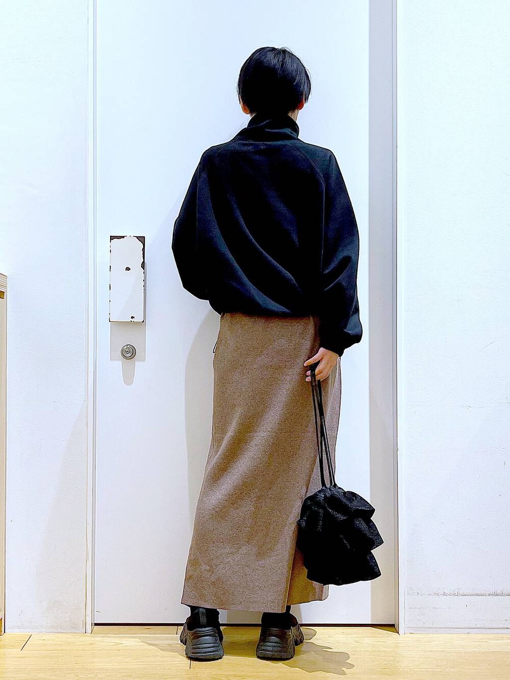 ブラック系のブーツ、ブラウン系のスカート、ブラック系のスウェットを着用したレディースの冬コーディネートの5枚目の写真