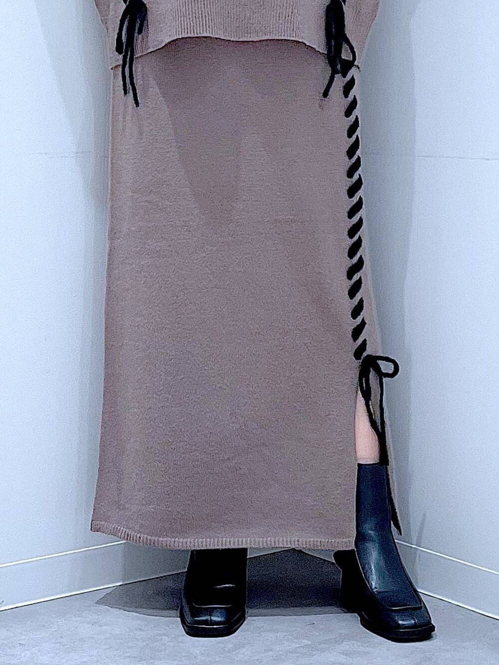 ブラウン系のニット/セーター、ブラウン系のスカート、ブラック系のブーツを着用したレディースの秋コーディネートの8枚目の写真