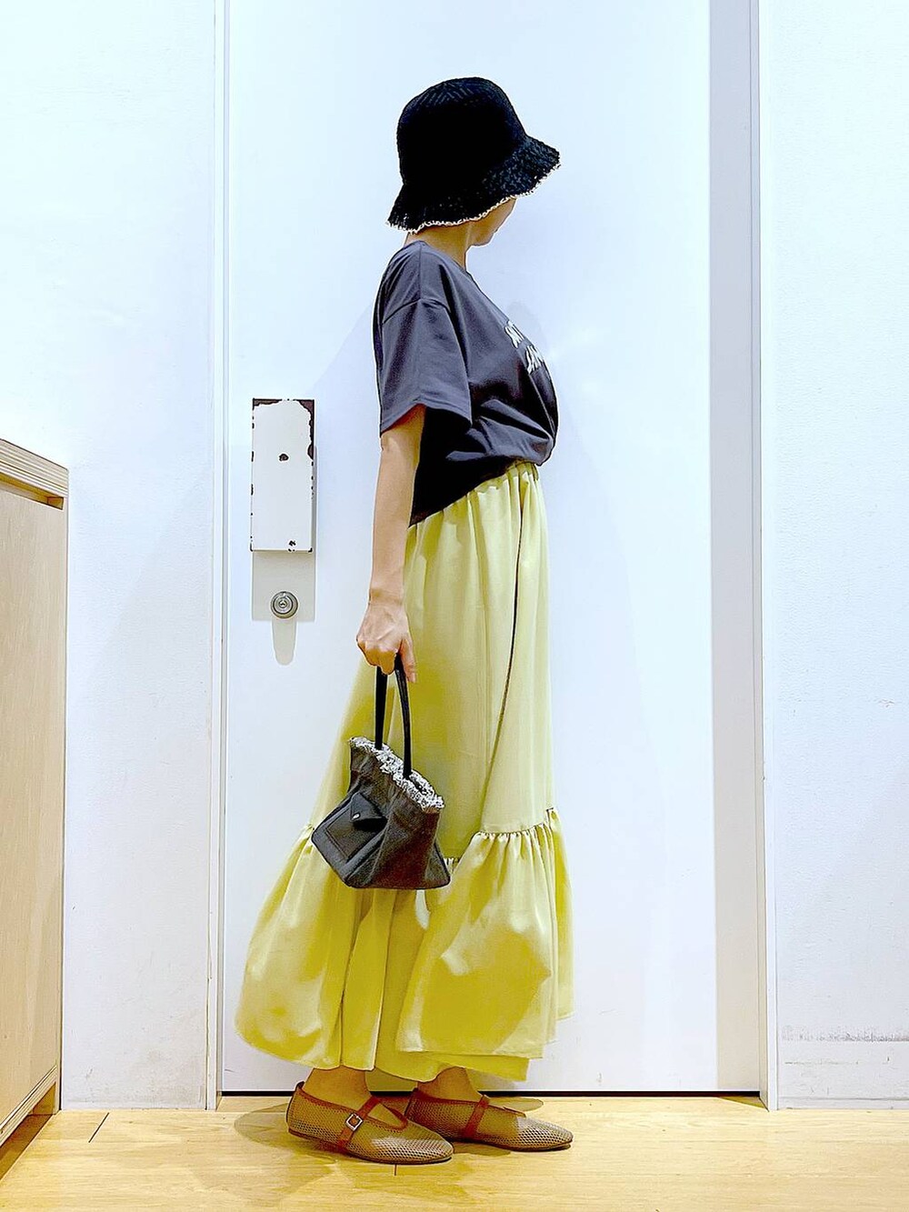 ブラック系のショルダーバッグ、ベージュ系のパンプス、イエロー系のワンピースを着用したレディースの春コーディネートの4枚目の写真