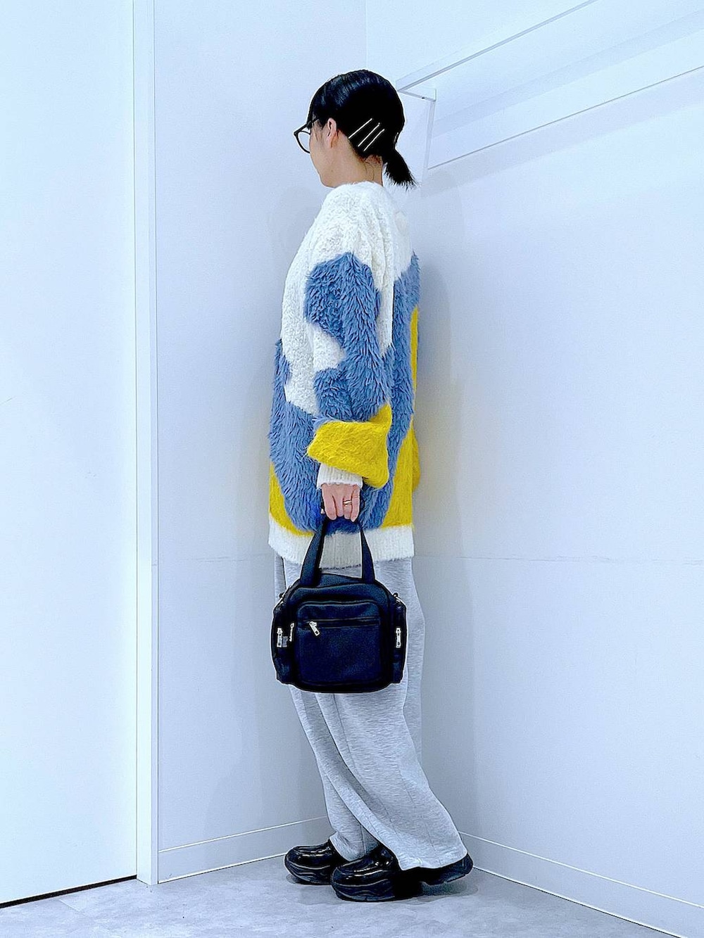 ブラック系のショルダーバッグ、ブラック系のローファー、イエロー系のカーディガン/ボレロを着用したレディースの秋コーディネートの3枚目の写真