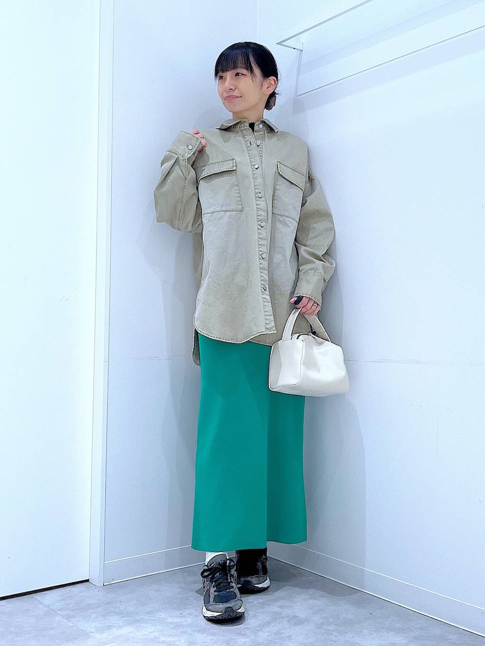 ホワイト系のショルダーバッグ、ベージュ系のシャツ/ブラウス、グリーン系のスカートを着用したレディースの春コーディネートの2枚目の写真