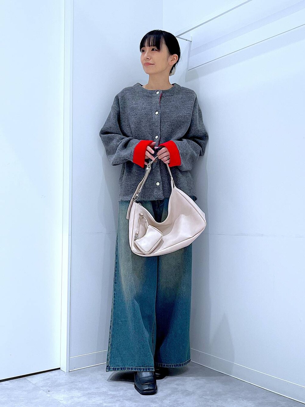 ブルー系のデニムパンツ、ブラック系のブーツ、ホワイト系のショルダーバッグを着用したレディースの冬コーディネートの2枚目の写真