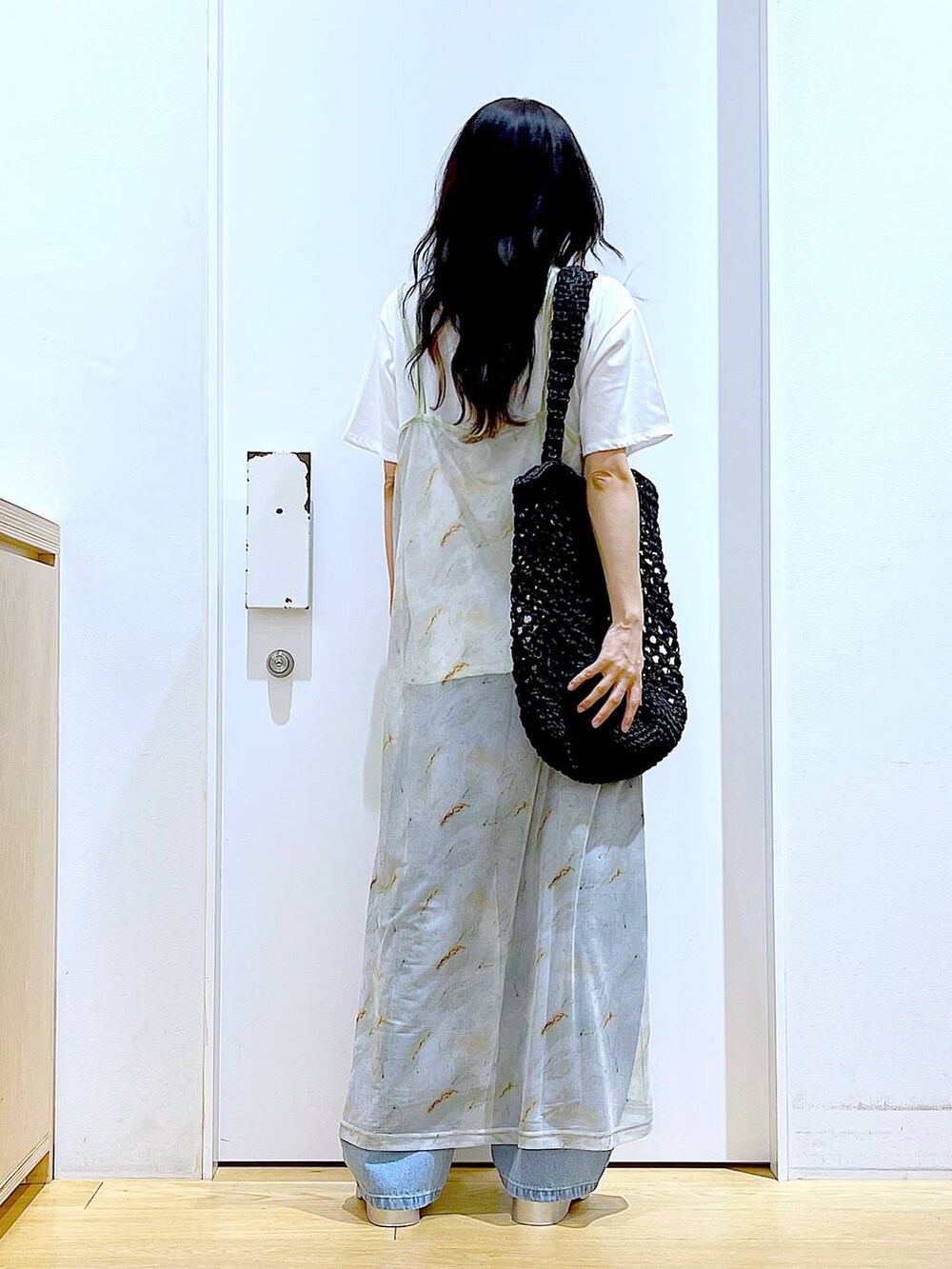 ブルー系のデニムパンツ、ブラック系のトートバッグ、ホワイト系のTシャツ/カットソーを着用したレディースの夏コーディネートの5枚目の写真