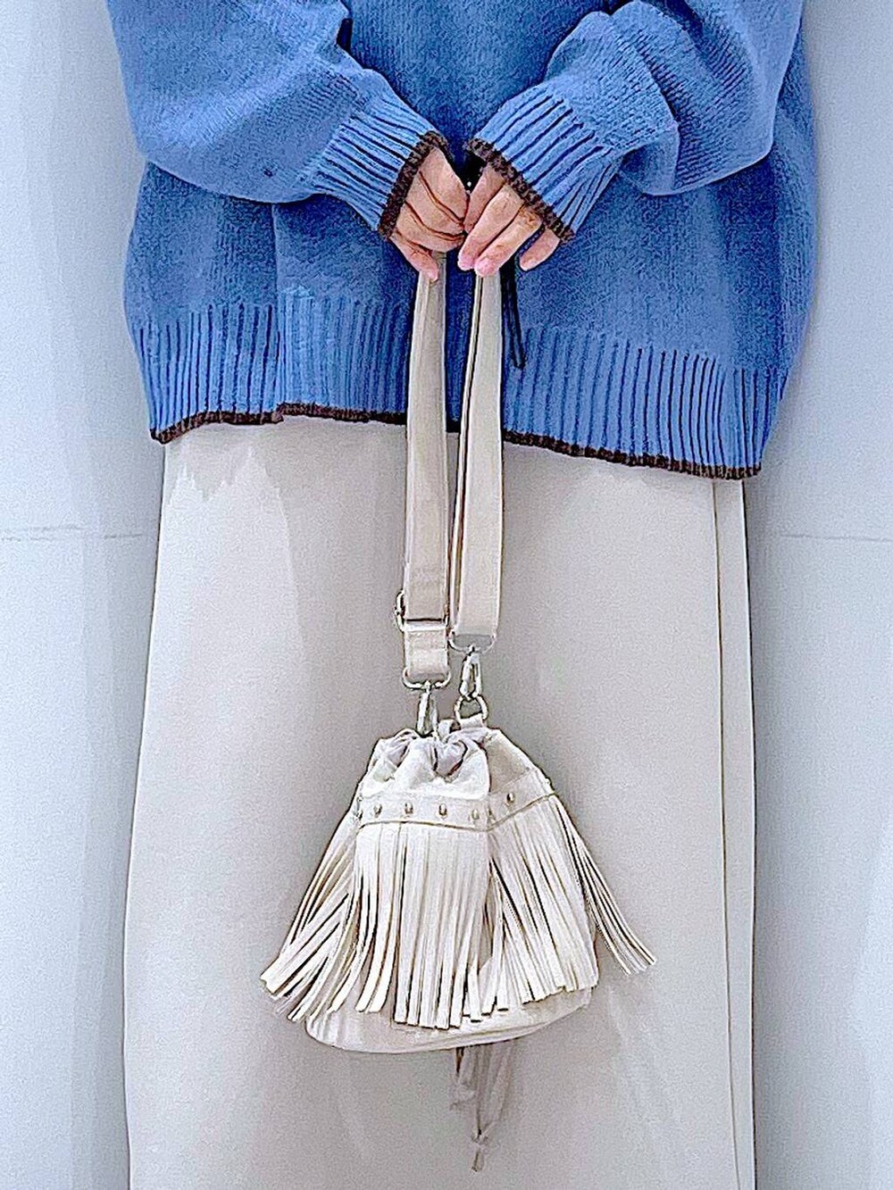 ベージュ系のスカート、ブラック系のブーツ、ホワイト系のショルダーバッグを着用したレディースの冬コーディネートの9枚目の写真