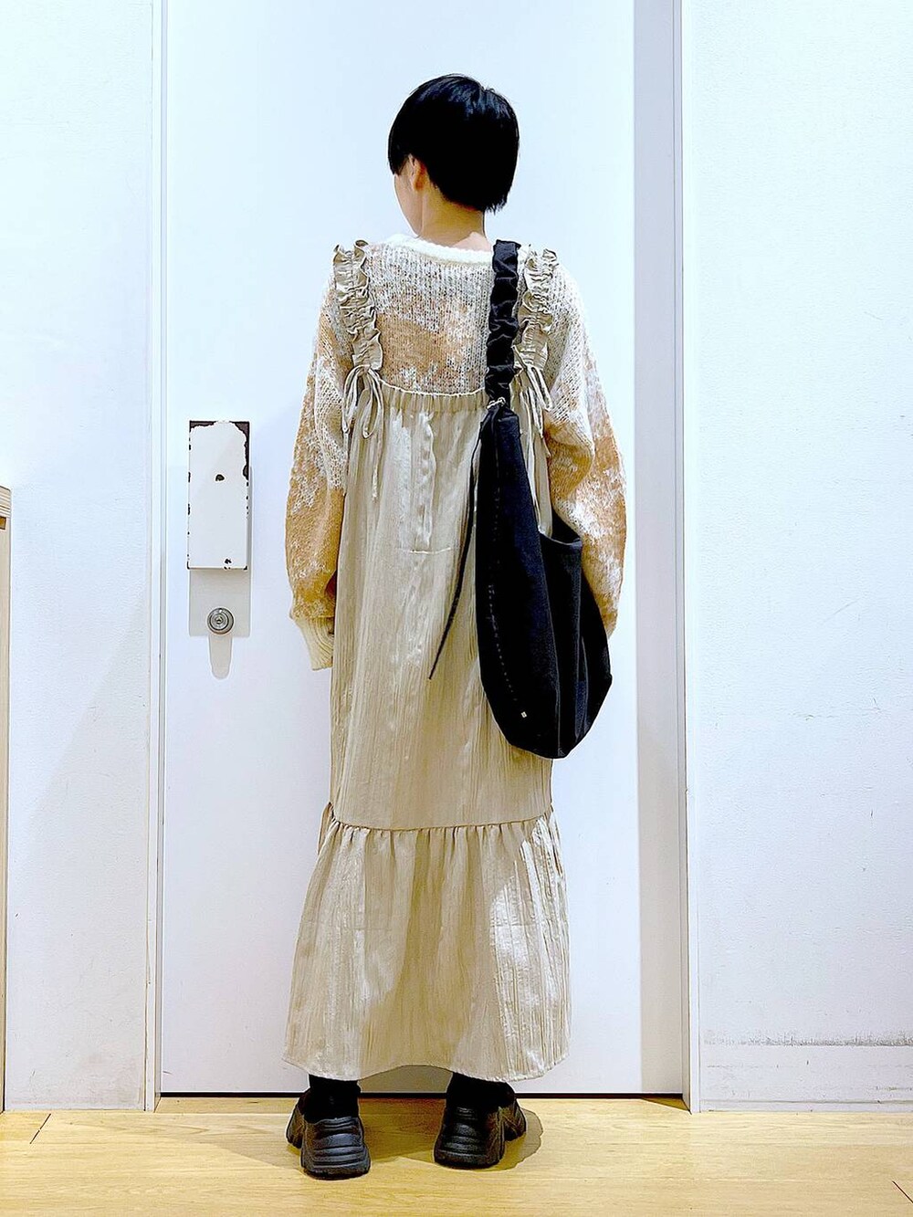 ブラック系のショルダーバッグ、ブラック系のブーツ、ベージュ系のワンピースを着用したレディースの冬コーディネートの5枚目の写真