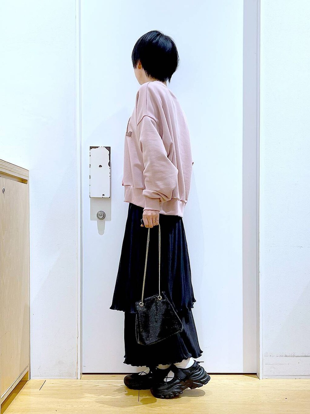 ブラック系のショルダーバッグ、ブラック系のスニーカー、ピンク系のスウェットを着用したレディースの春コーディネートの3枚目の写真