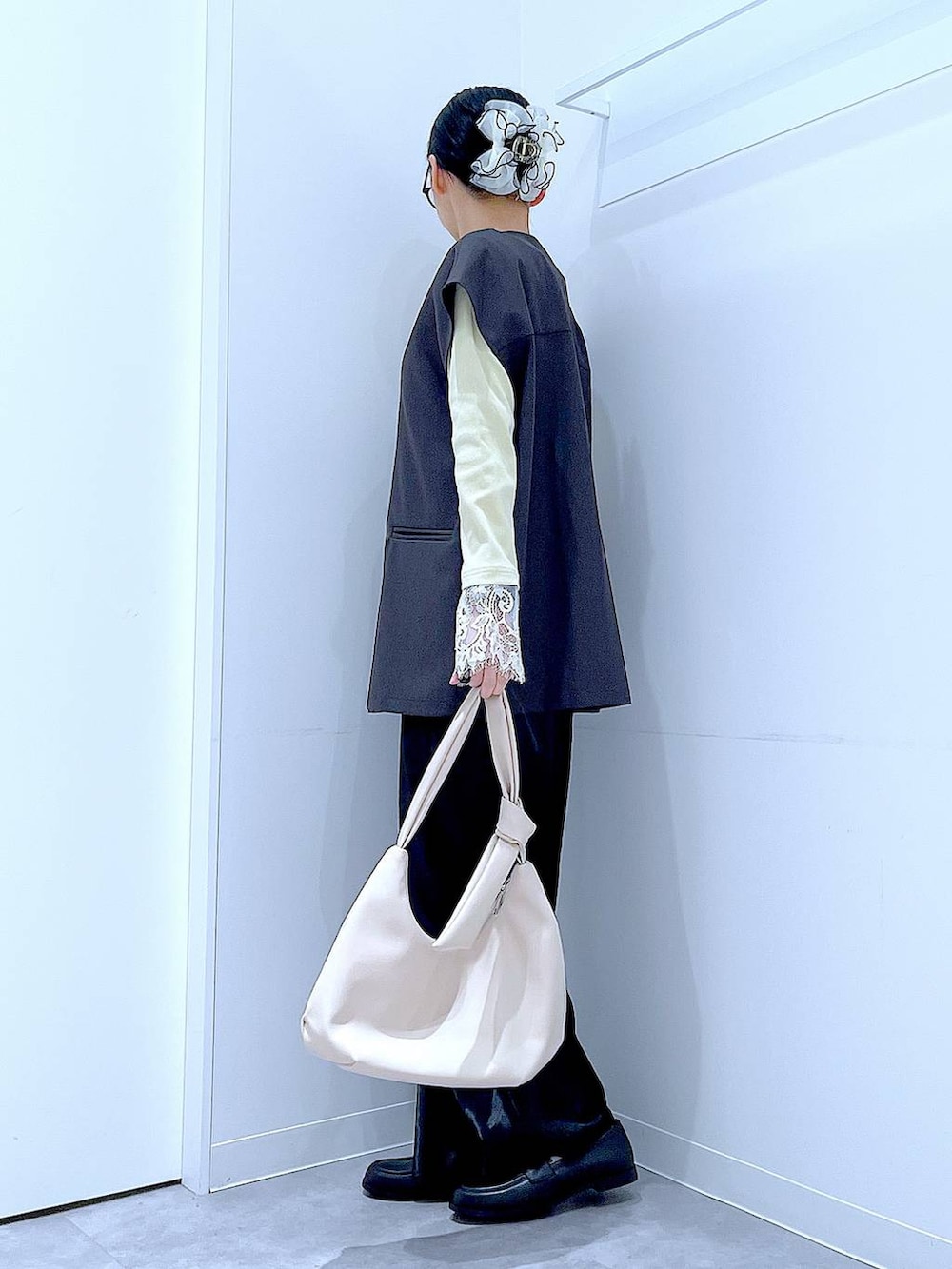 ブラック系のスカート、グレー系のベスト、ブラック系のローファーを着用したレディースの春コーディネートの3枚目の写真