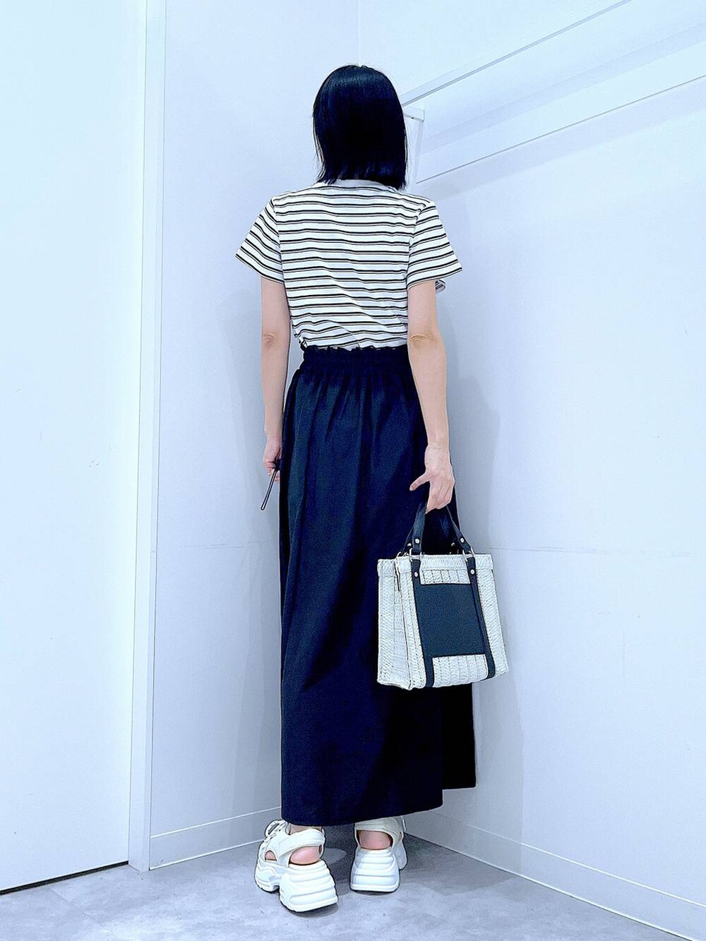 ホワイト系のショルダーバッグ、ホワイト系のサンダル、ベージュ系のTシャツ/カットソーを着用したレディースの夏コーディネートの5枚目の写真
