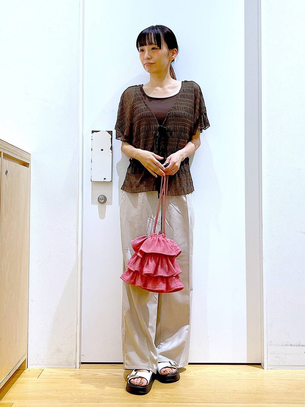 ホワイト系のサンダル、ベージュ系のスラックス、ピンク系のショルダーバッグを着用したレディースの秋コーディネートの2枚目の写真