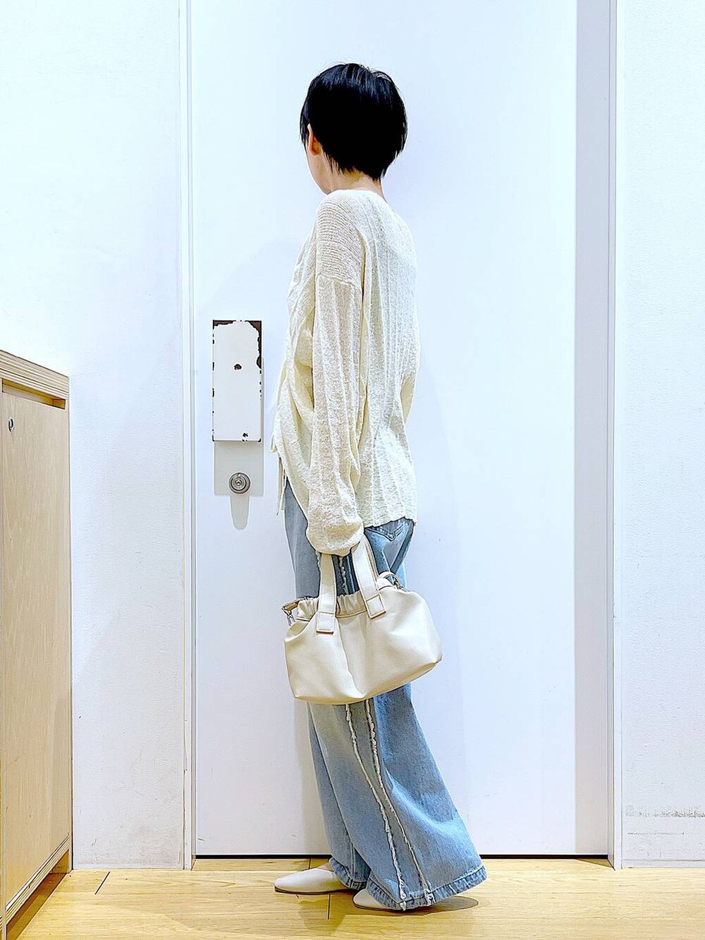 ホワイト系のショルダーバッグ、ホワイト系のパンプス、ブルー系のデニムパンツを着用したレディースの春コーディネートの3枚目の写真