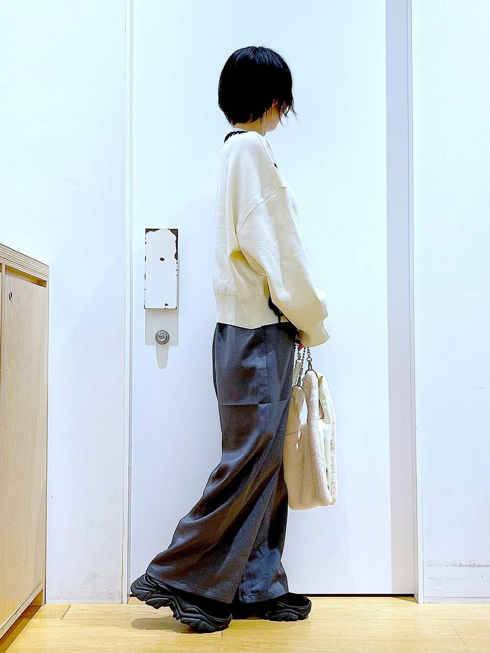 ホワイト系のショルダーバッグ、ブラック系のブーツ、グレー系のその他パンツを着用したレディースの冬コーディネートの4枚目の写真