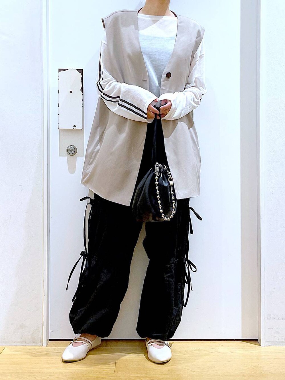 ブラック系のショルダーバッグ、ホワイト系のパンプス、ブラック系のその他パンツを着用したレディースの秋コーディネートの6枚目の写真