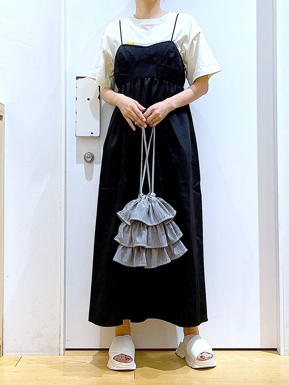 ホワイト系のサンダル、ベージュ系のTシャツ/カットソー、ブラック系のワンピースを着用したレディースの夏コーディネートの6枚目の写真