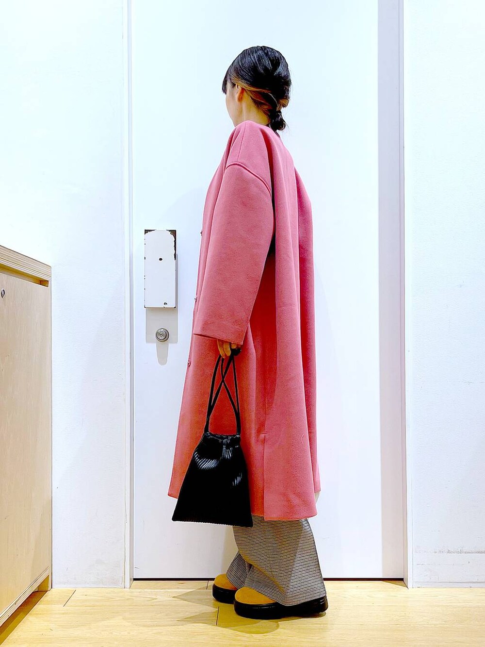 ブラック系のショルダーバッグ、ブラック系のニット/セーター、ベージュ系のスラックスを着用したレディースの冬コーディネートの3枚目の写真