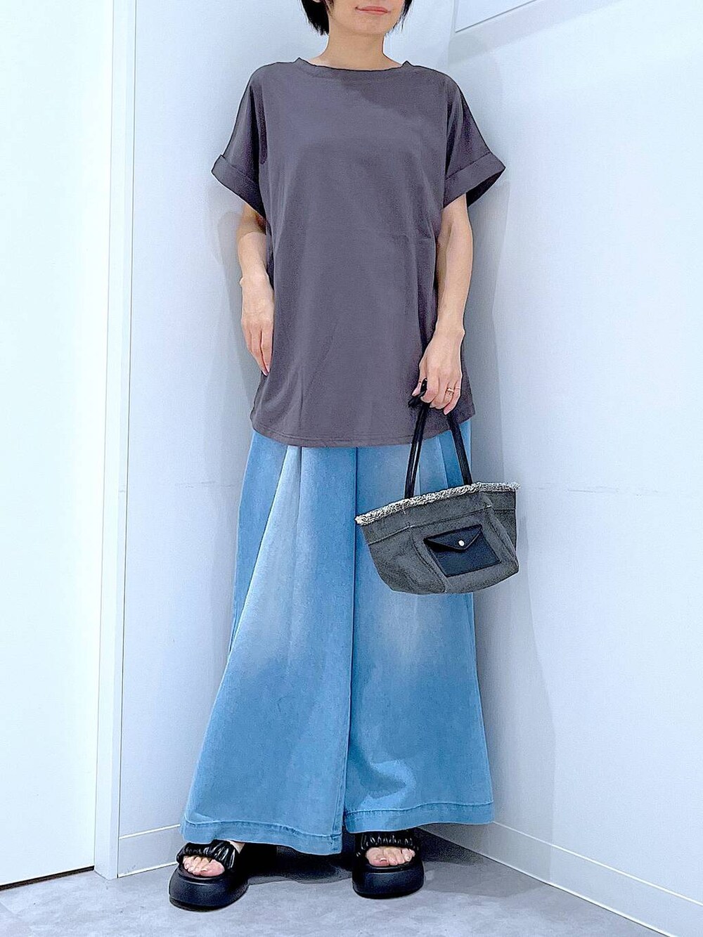 ブラック系のショルダーバッグ、ブラック系のサンダル、ブルー系のデニムパンツを着用したレディースの夏コーディネートの6枚目の写真