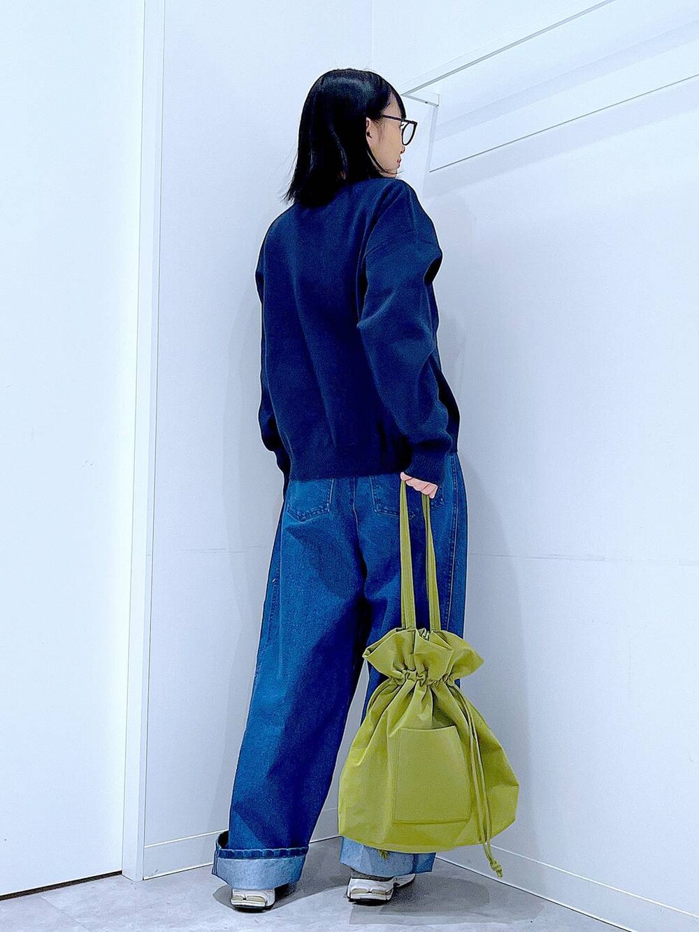 グリーン系のトートバッグ、ブルー系のニット/セーター、ブルー系のデニムパンツを着用したレディースの冬コーディネートの5枚目の写真