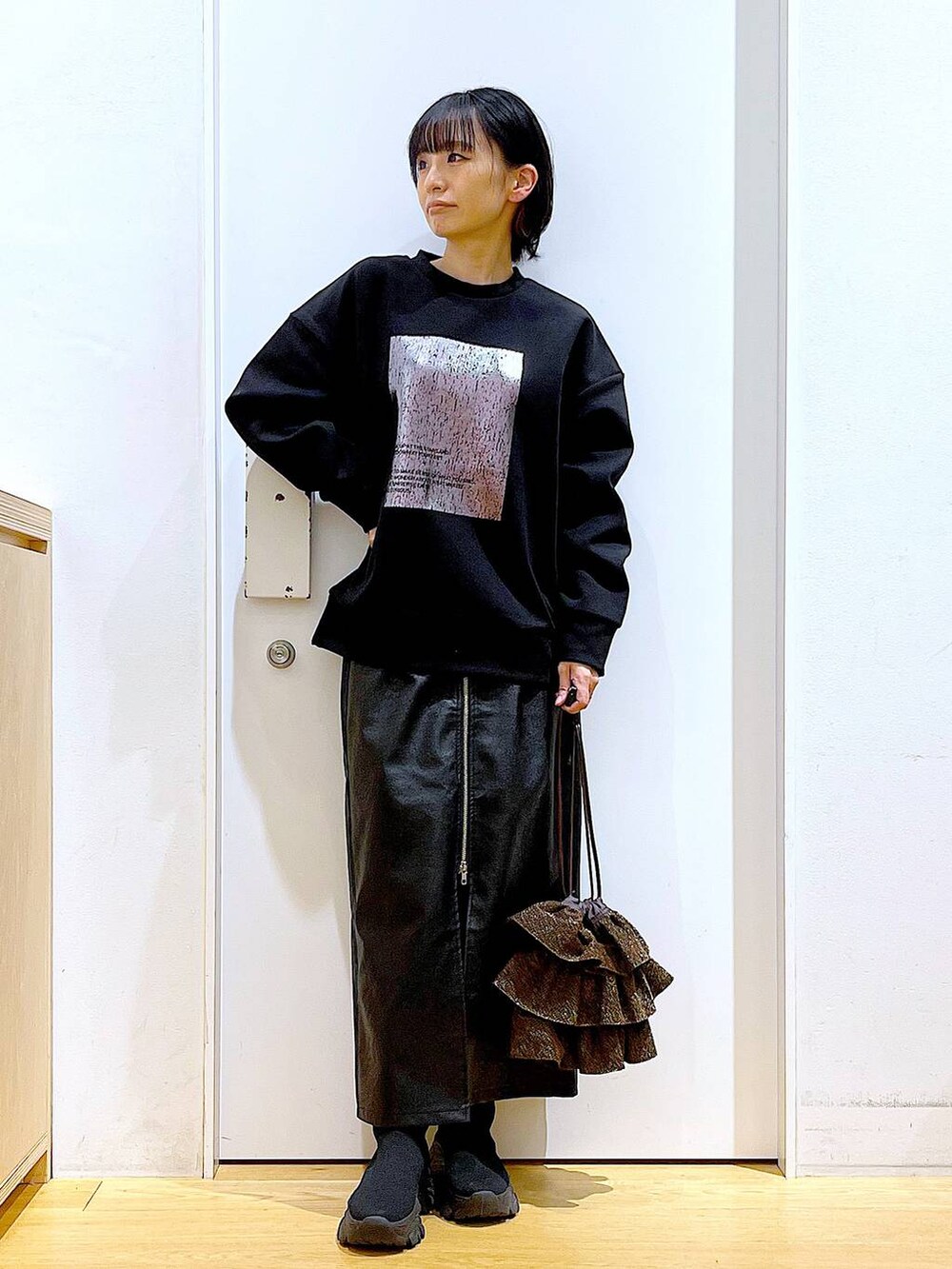 ブラック系のスカート、ブラック系のブーツ、ブラウン系のショルダーバッグを着用したレディースの冬コーディネートの2枚目の写真